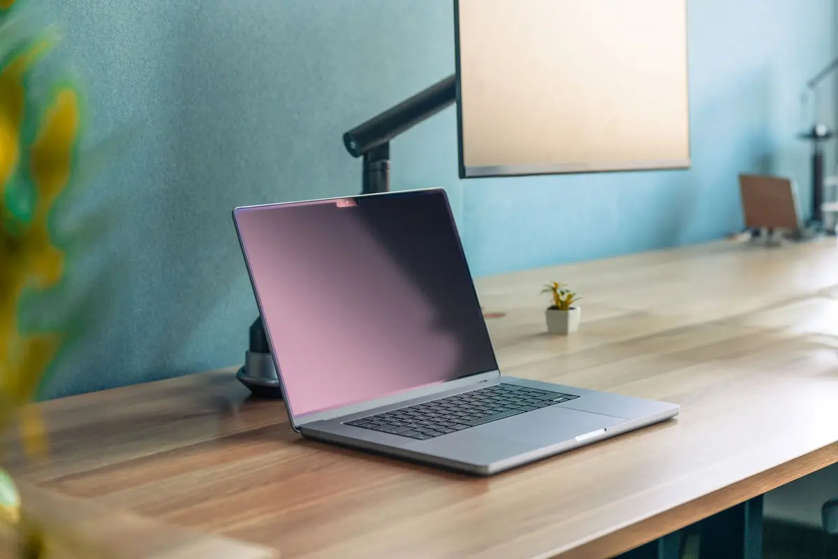 Un ordinateur portable ouvert sur un bureau en bois, dans un espace de travail lumineux